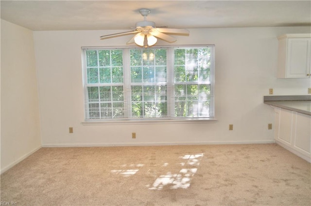 unfurnished dining area featuring light carpet and ceiling fan