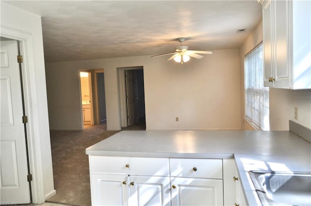 kitchen with dark carpet, white cabinets, and ceiling fan