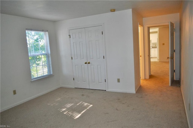 unfurnished bedroom featuring light carpet and a closet