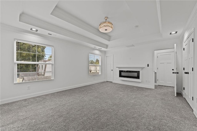 unfurnished living room featuring a tray ceiling, crown molding, and carpet