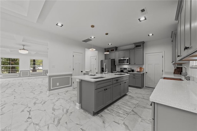 kitchen featuring stainless steel appliances, gray cabinetry, sink, hanging light fixtures, and a center island with sink