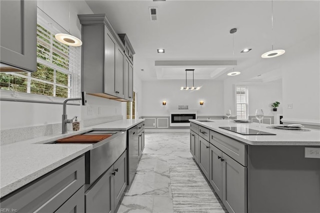 kitchen featuring a center island with sink, gray cabinetry, and black electric stovetop