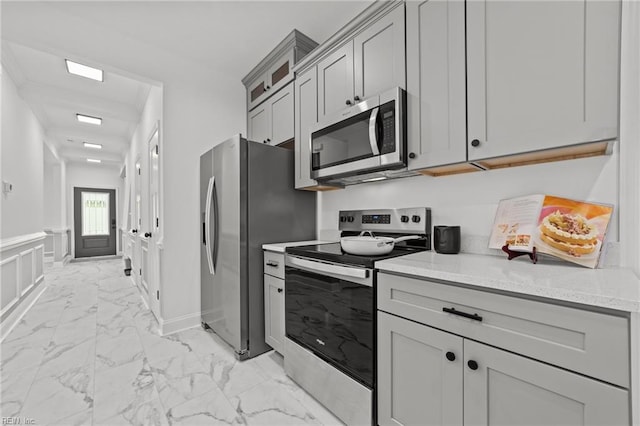 kitchen with gray cabinetry, light stone countertops, and stainless steel appliances