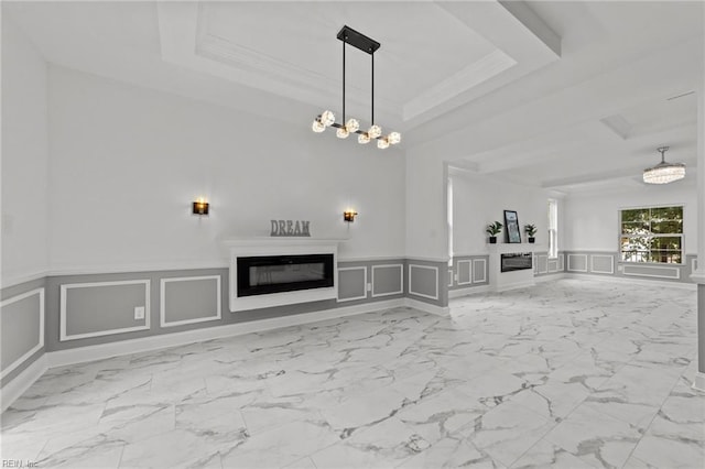 unfurnished living room with crown molding, a tray ceiling, and a chandelier