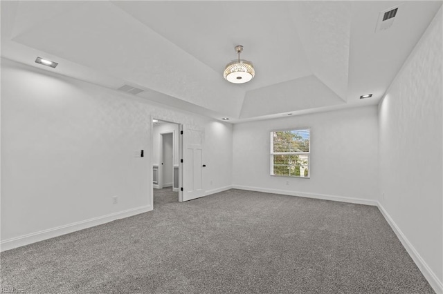 carpeted empty room featuring a tray ceiling