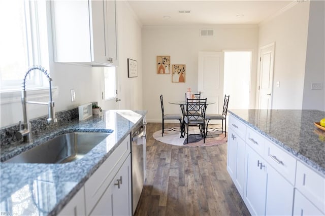 kitchen with light stone counters, white cabinetry, and sink