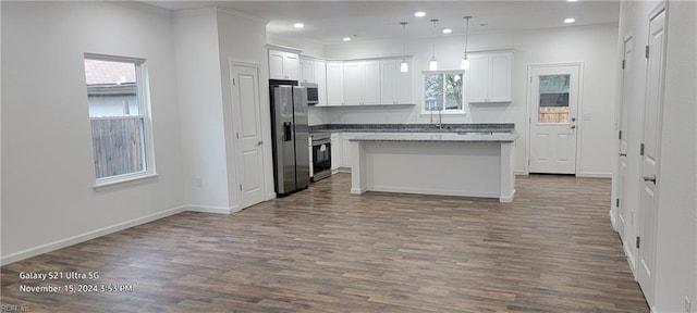 kitchen featuring a center island, white cabinets, hanging light fixtures, appliances with stainless steel finishes, and wood-type flooring