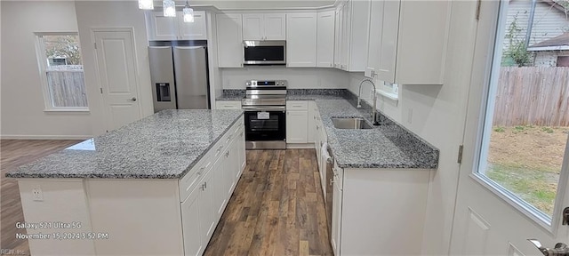 kitchen featuring stainless steel appliances, white cabinetry, a wealth of natural light, and sink