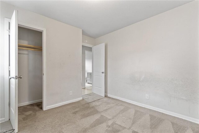 unfurnished bedroom with light carpet and a closet