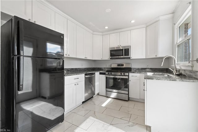 kitchen featuring dark stone countertops, white cabinets, stainless steel appliances, and sink