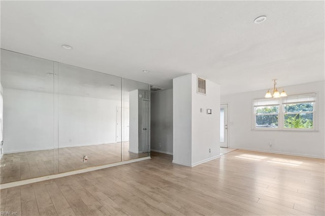 unfurnished room featuring light wood-type flooring and an inviting chandelier