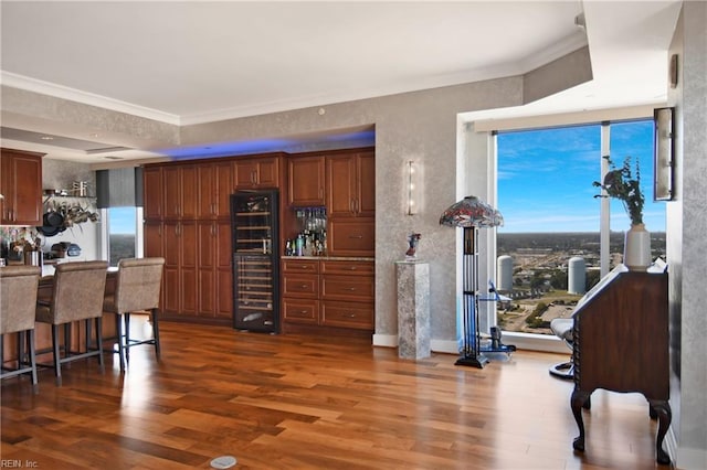 kitchen with dark hardwood / wood-style floors, crown molding, a breakfast bar area, and stainless steel fridge