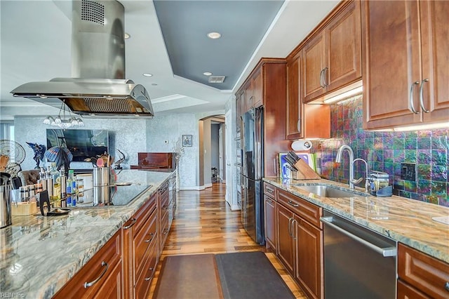 kitchen featuring light stone countertops, sink, island range hood, light hardwood / wood-style flooring, and appliances with stainless steel finishes