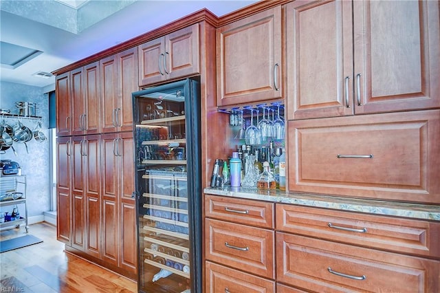 bar featuring light wood-style floors, freestanding refrigerator, a dry bar, visible vents, and wine cooler