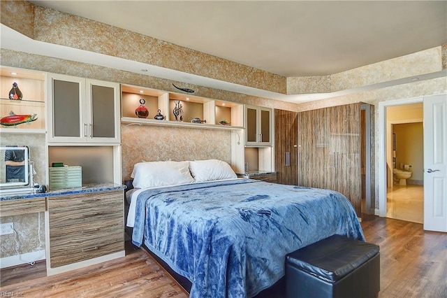 bedroom featuring ensuite bath and hardwood / wood-style floors