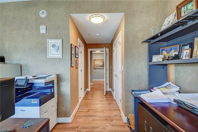 hallway featuring light wood-style flooring and baseboards