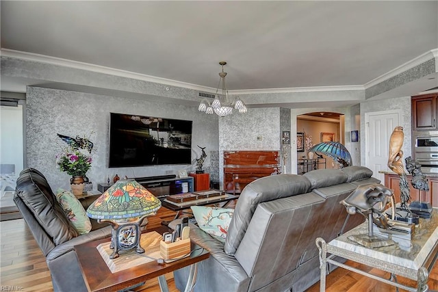 living room featuring ornamental molding, a chandelier, and light hardwood / wood-style flooring