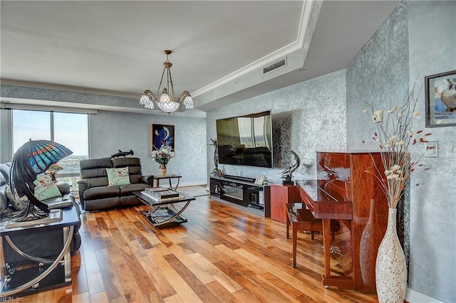 living room with ornamental molding, hardwood / wood-style floors, and a chandelier