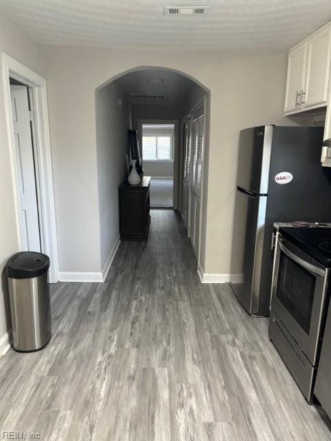 kitchen featuring light wood-type flooring, white cabinets, and stainless steel electric range