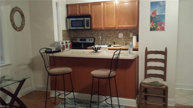 kitchen featuring tasteful backsplash, a breakfast bar area, and range with electric stovetop