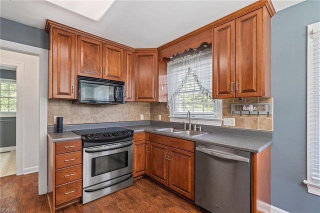 kitchen with appliances with stainless steel finishes, a wealth of natural light, dark wood-type flooring, and tasteful backsplash