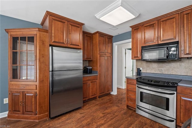 kitchen with appliances with stainless steel finishes, dark wood-type flooring, and tasteful backsplash