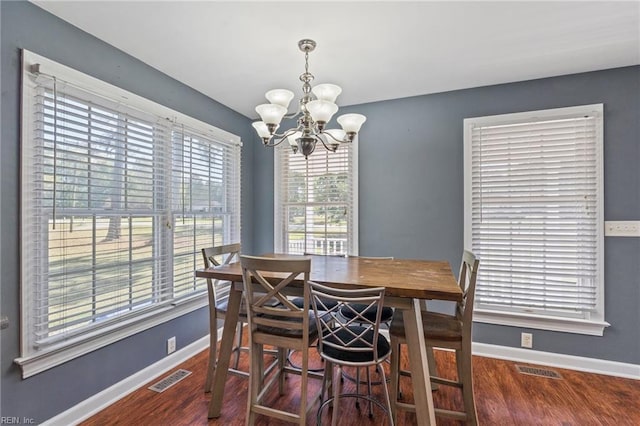 dining space with dark hardwood / wood-style floors and a notable chandelier