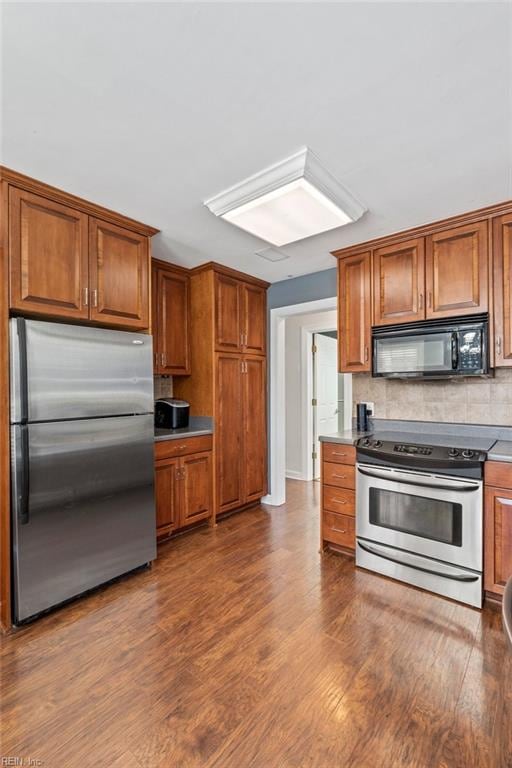 kitchen with stainless steel appliances, dark hardwood / wood-style floors, and backsplash