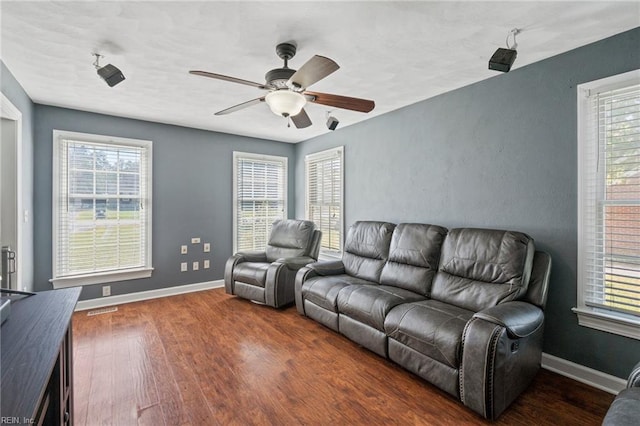 living room featuring a healthy amount of sunlight, ceiling fan, and dark hardwood / wood-style flooring