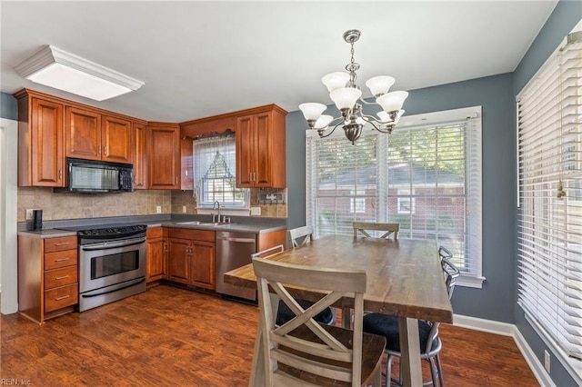 kitchen with appliances with stainless steel finishes, decorative backsplash, a chandelier, and dark hardwood / wood-style flooring