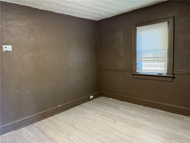 spare room with a textured ceiling and light hardwood / wood-style floors