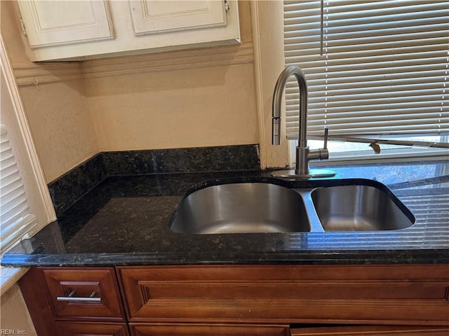 room details featuring dark stone countertops and sink