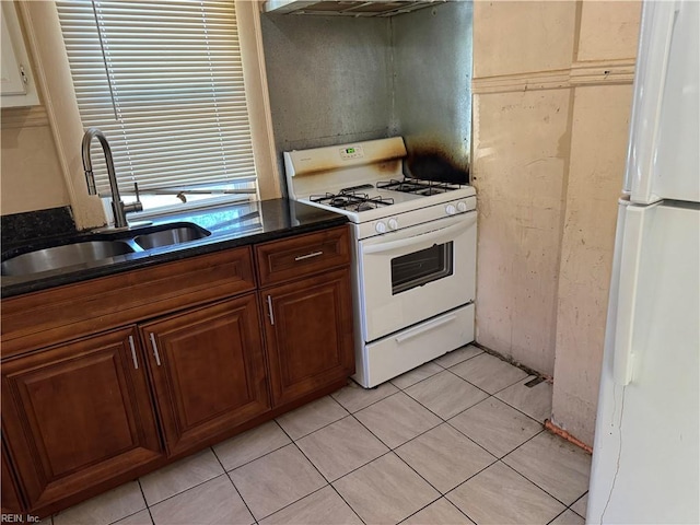 kitchen featuring white appliances, exhaust hood, dark stone counters, sink, and light tile patterned flooring