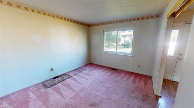 carpeted spare room featuring a textured ceiling