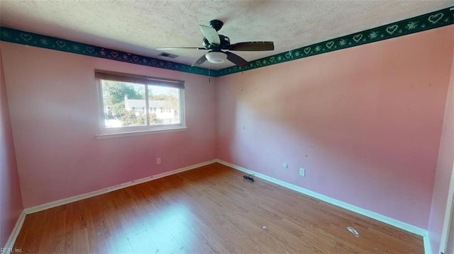 unfurnished room with ceiling fan, wood-type flooring, and a textured ceiling