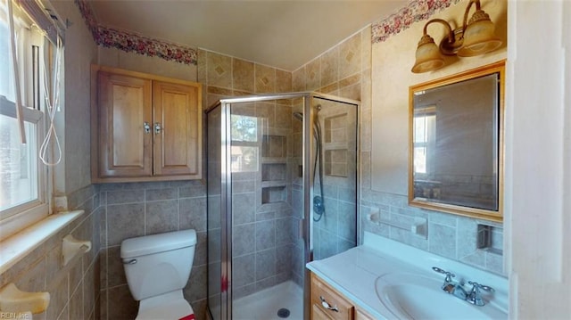 bathroom with vanity, toilet, a shower with shower door, and plenty of natural light