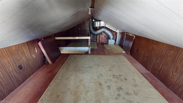 additional living space featuring vaulted ceiling, carpet floors, and wood walls