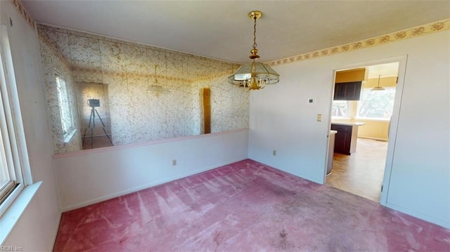 carpeted spare room with a notable chandelier