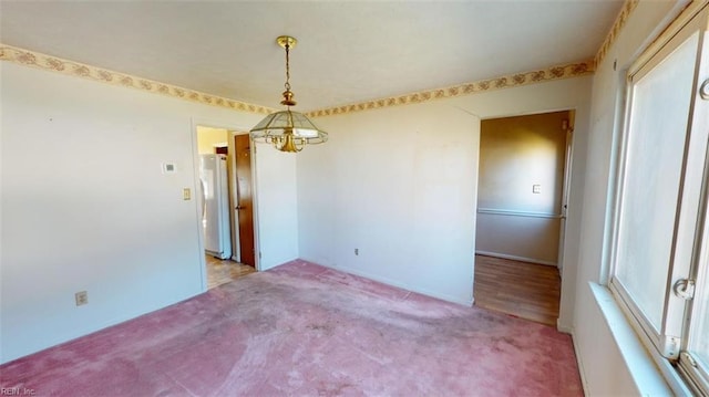 unfurnished room featuring a healthy amount of sunlight, light carpet, and a notable chandelier