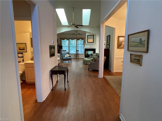 corridor featuring ornamental molding, dark hardwood / wood-style floors, and a skylight