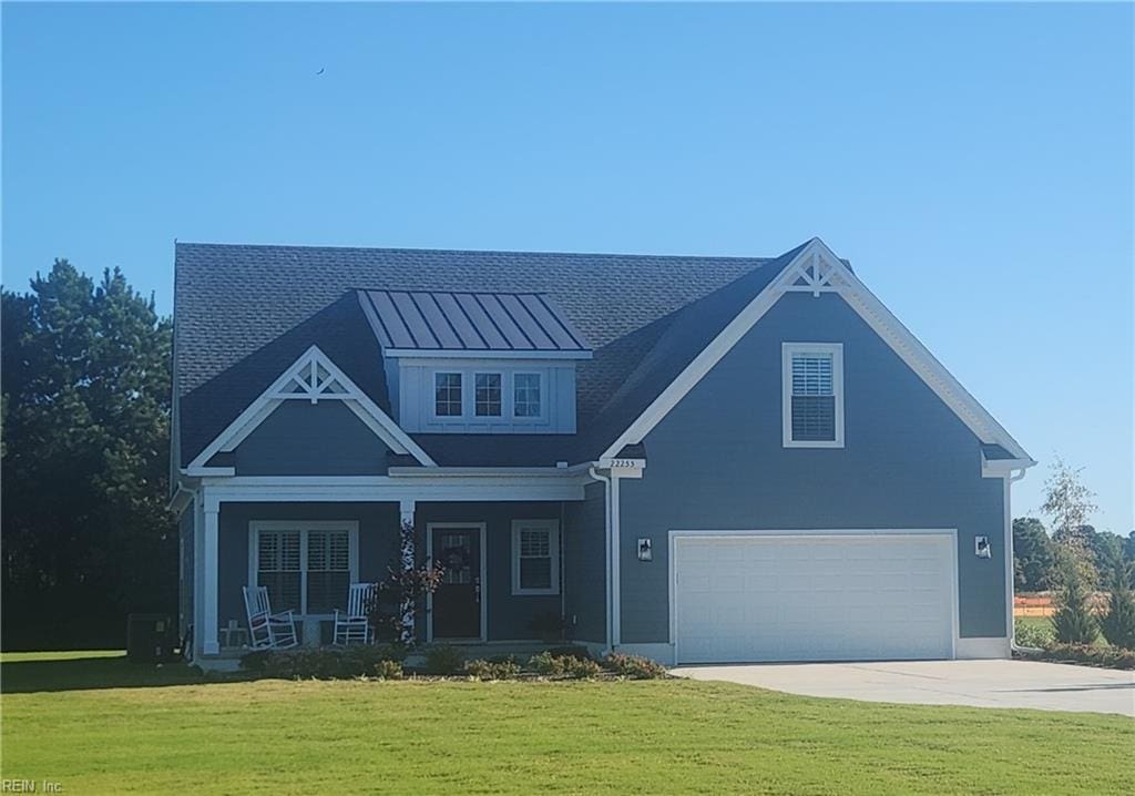 view of front facade with covered porch, a garage, and a front yard