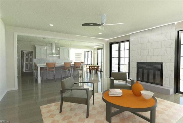 sitting room featuring a tiled fireplace and ceiling fan