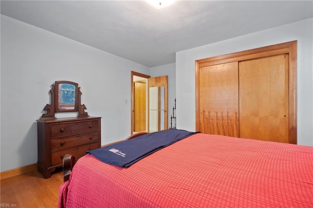 bedroom with a closet, hardwood / wood-style floors, and white fridge