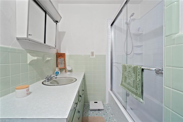 bathroom featuring combined bath / shower with glass door, tile patterned floors, vanity, and tile walls