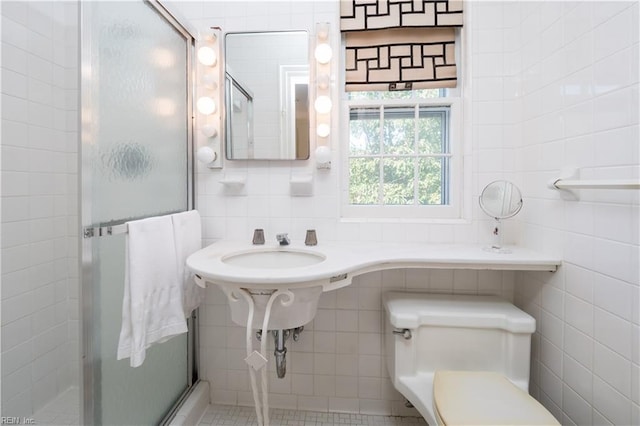 bathroom featuring toilet, tile walls, and a shower with door