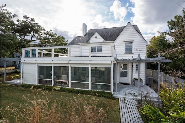 back of property featuring a yard, a sunroom, a pergola, and central AC unit