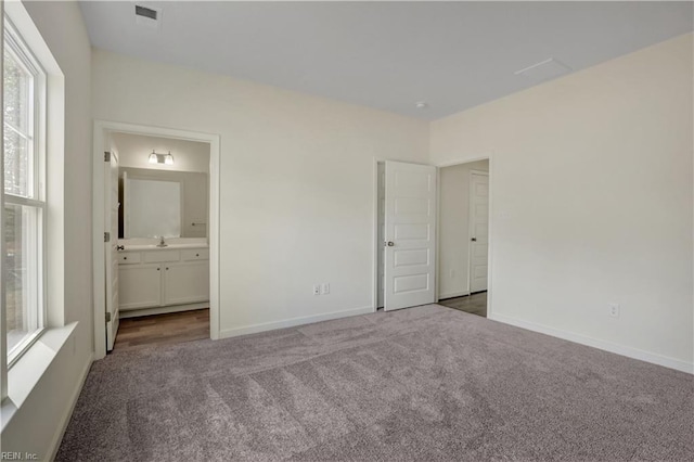 unfurnished bedroom featuring ensuite bath, carpet, baseboards, and visible vents