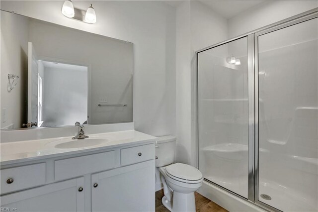 full bathroom featuring vanity, a shower stall, and toilet