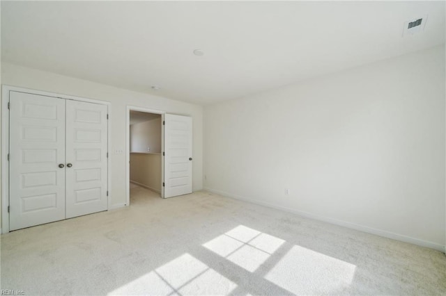 unfurnished bedroom featuring baseboards, visible vents, and light colored carpet
