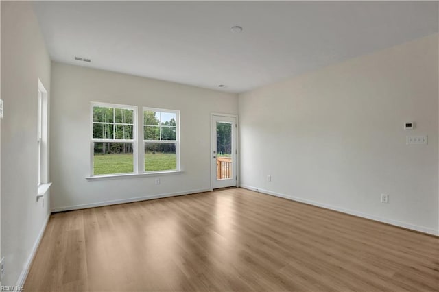 empty room featuring visible vents, baseboards, and wood finished floors